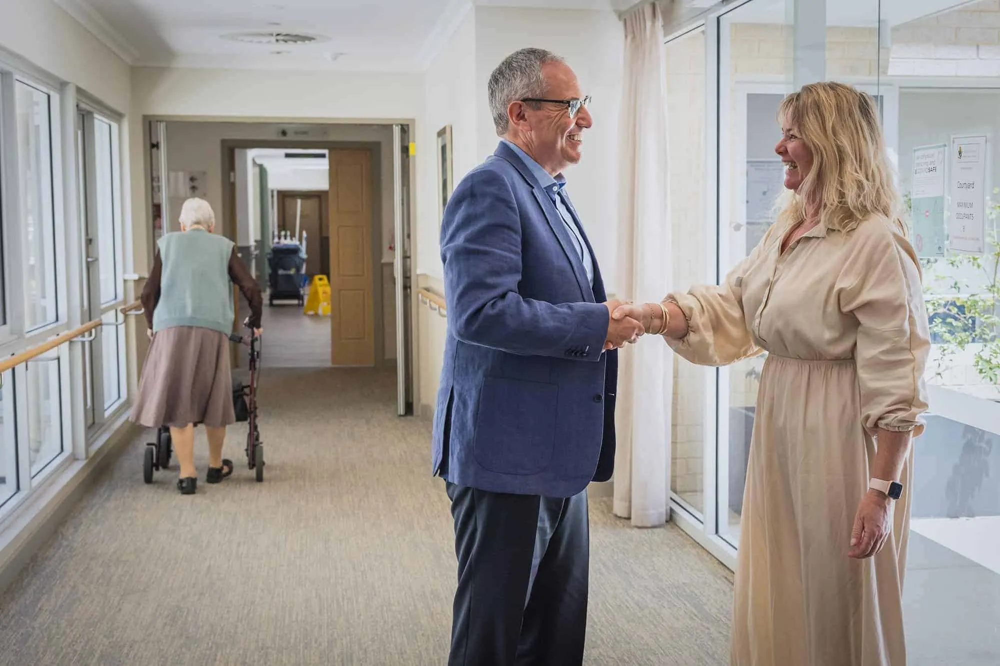 Lewis Chiat greeting a family member in the corridor of an aged care home